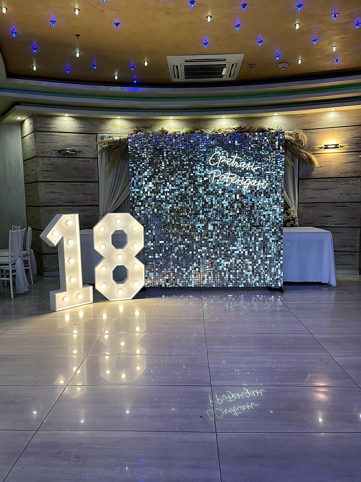 Svetleći broj 18 ispred shimmer zida u sali